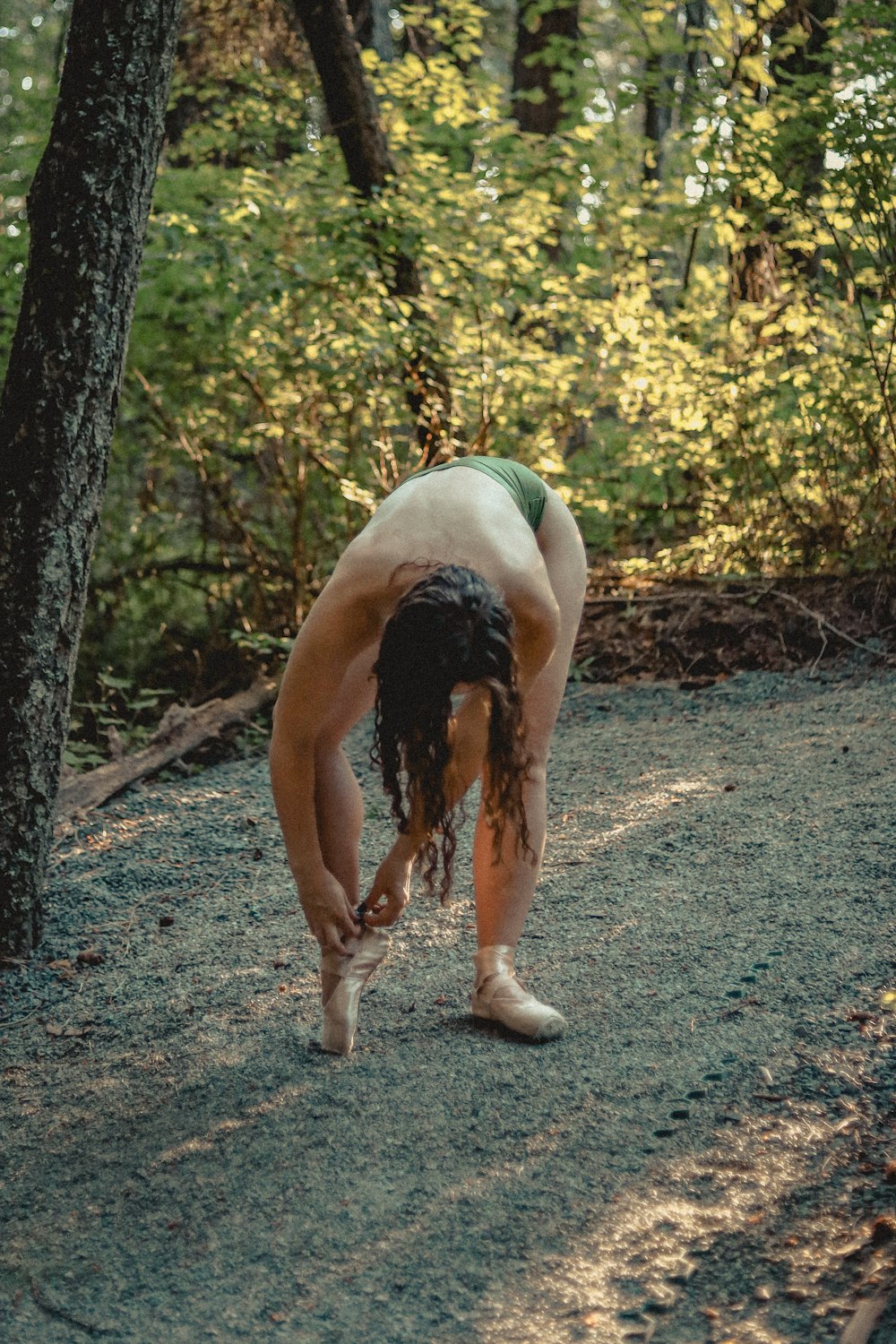 a man bending over on a dirt road in the woods