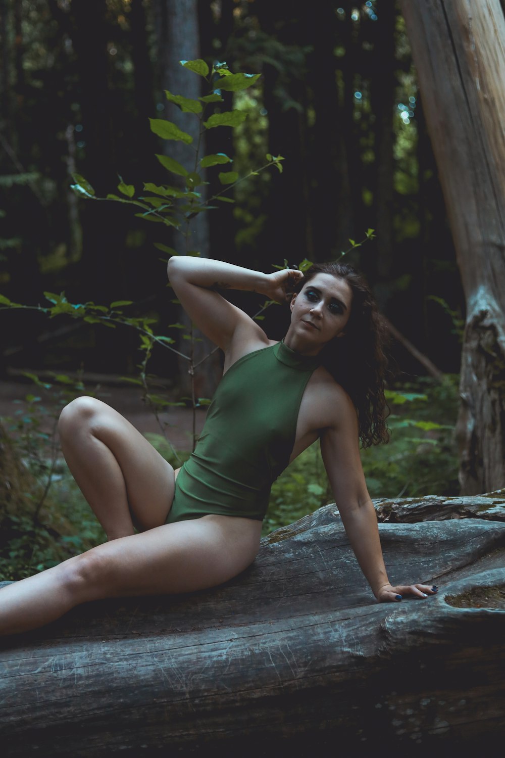 a woman is sitting on a log in the woods