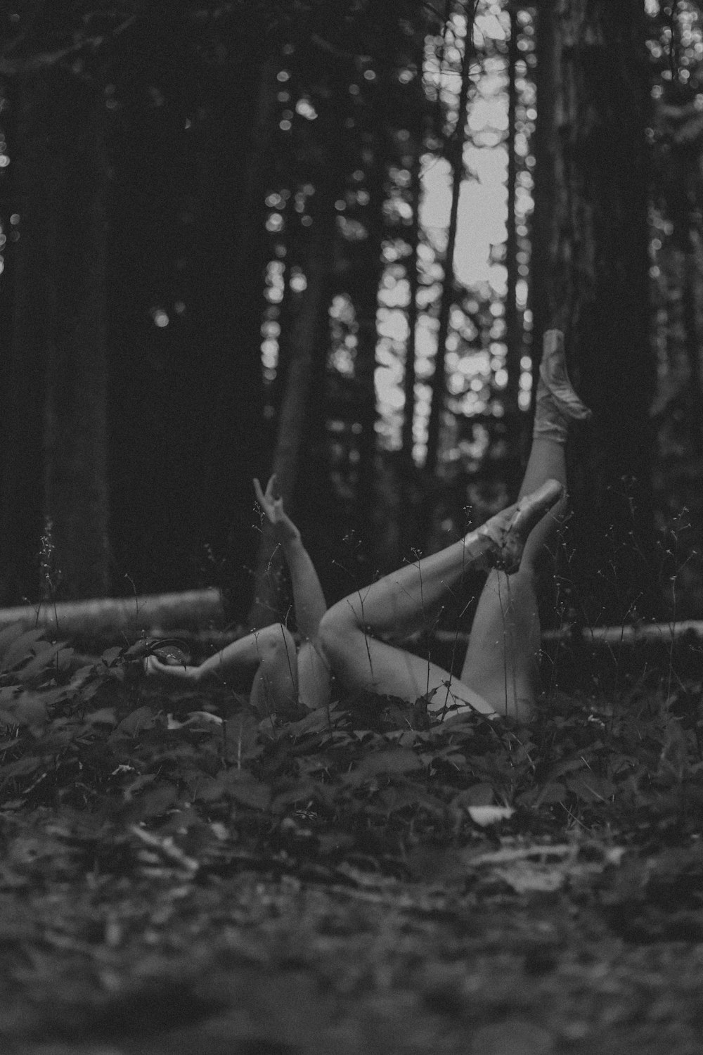 a woman laying on the ground in the woods