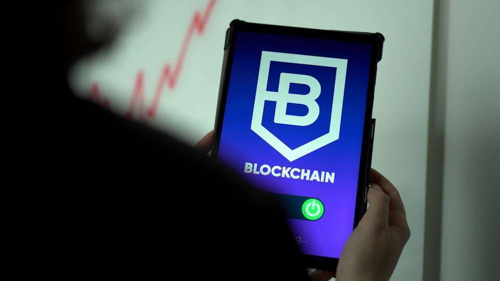 a person holding a cell phone with a blockchain logo on it