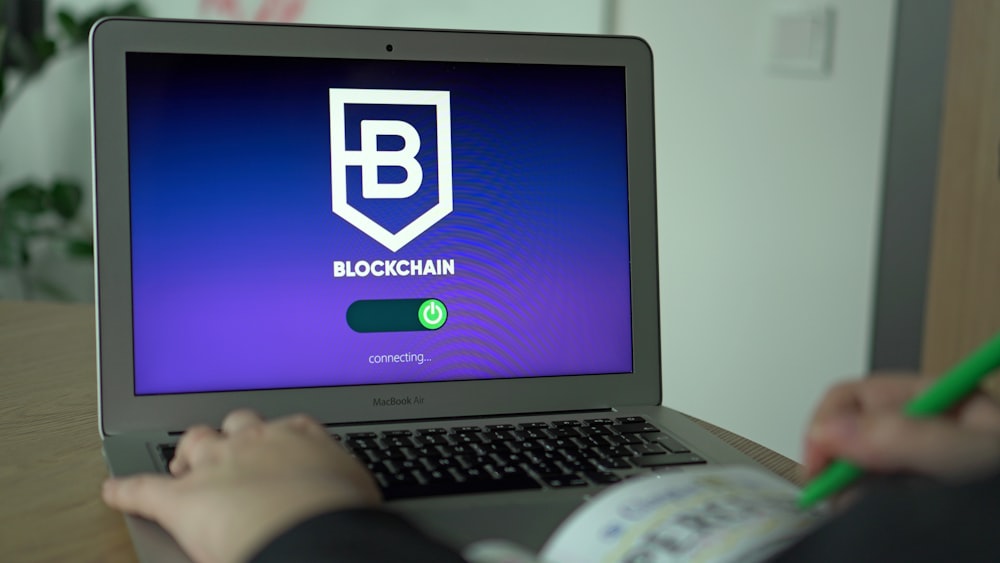 a person using a laptop with a blockchain logo on the screen