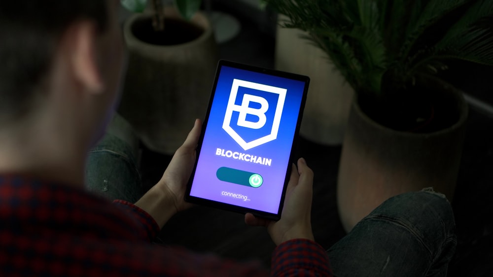 a person holding a tablet with a blockchain logo on it