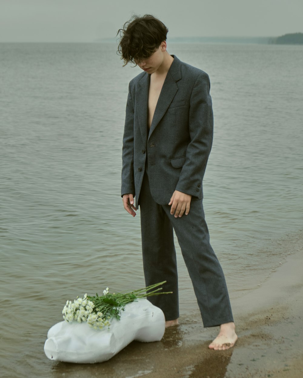 a man standing on a beach next to a body of water