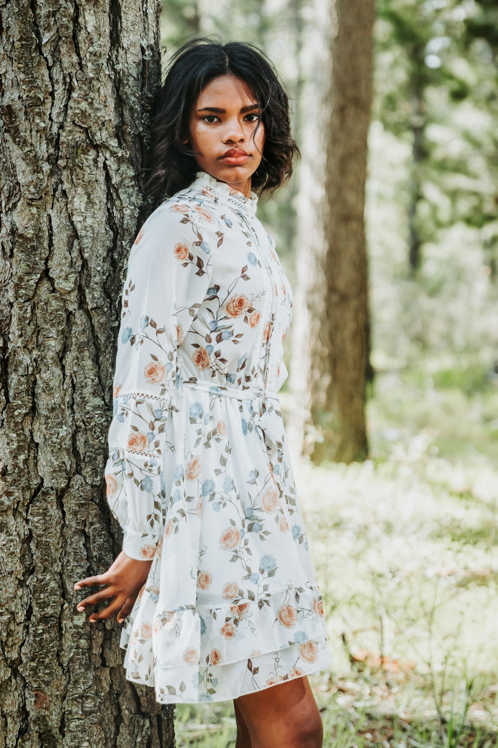 a woman leaning against a tree in a forest