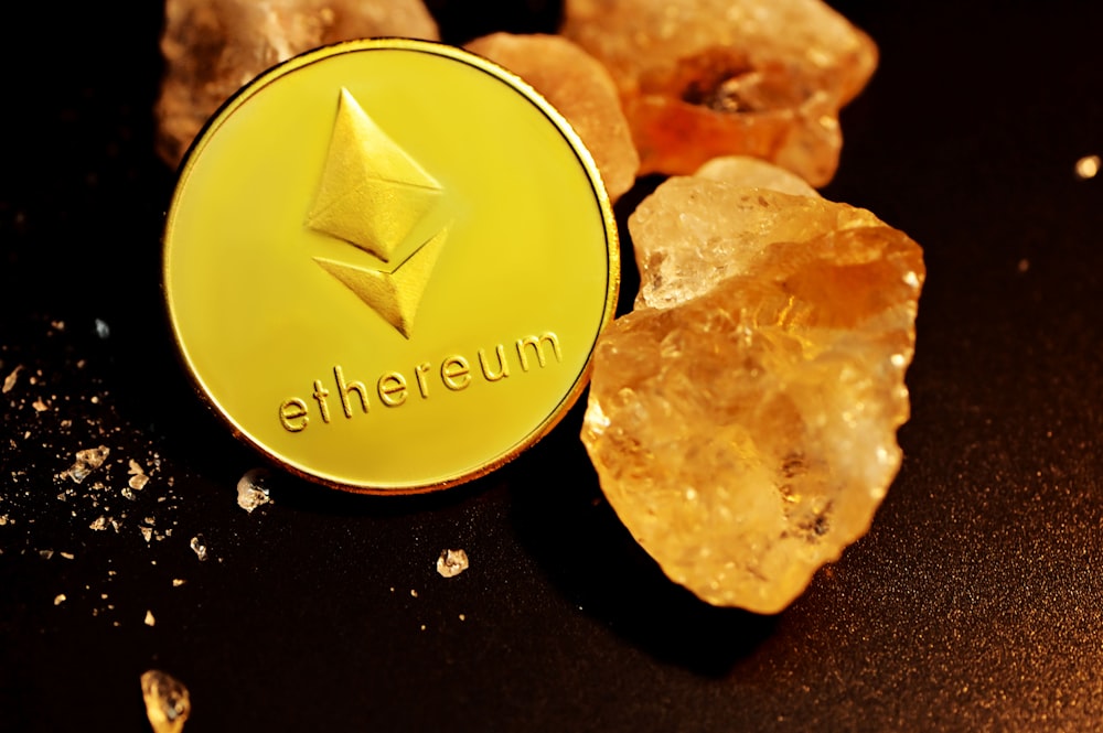 a gold ethereum coin sitting on top of a pile of rocks
