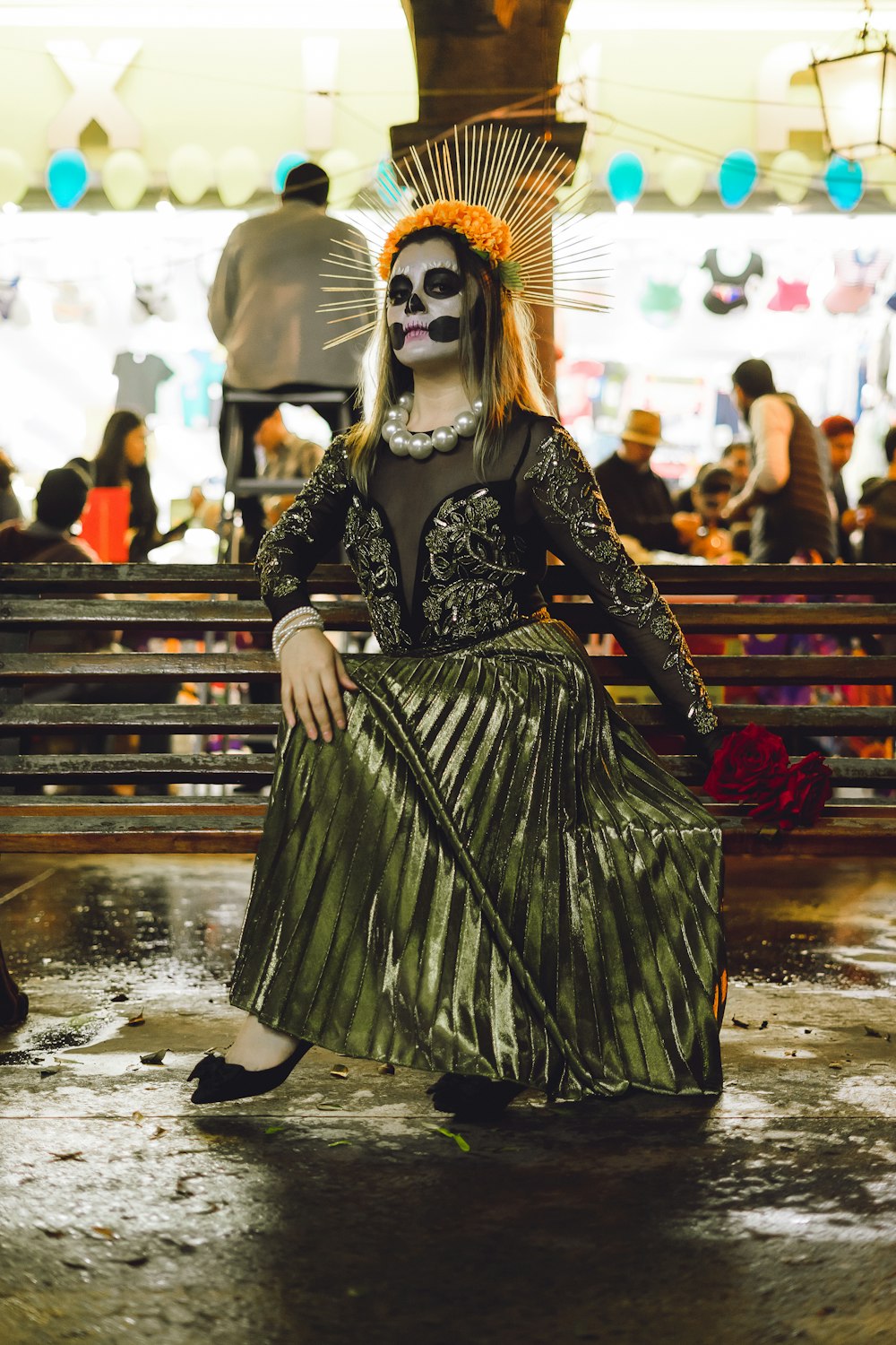 a woman in a skeleton mask and dress sitting on a bench