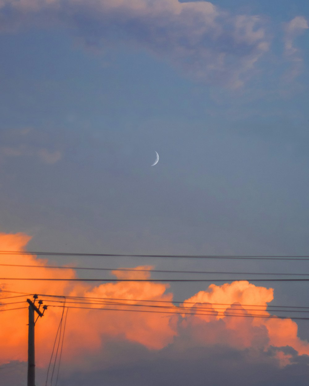 a full moon is seen in the sky above power lines