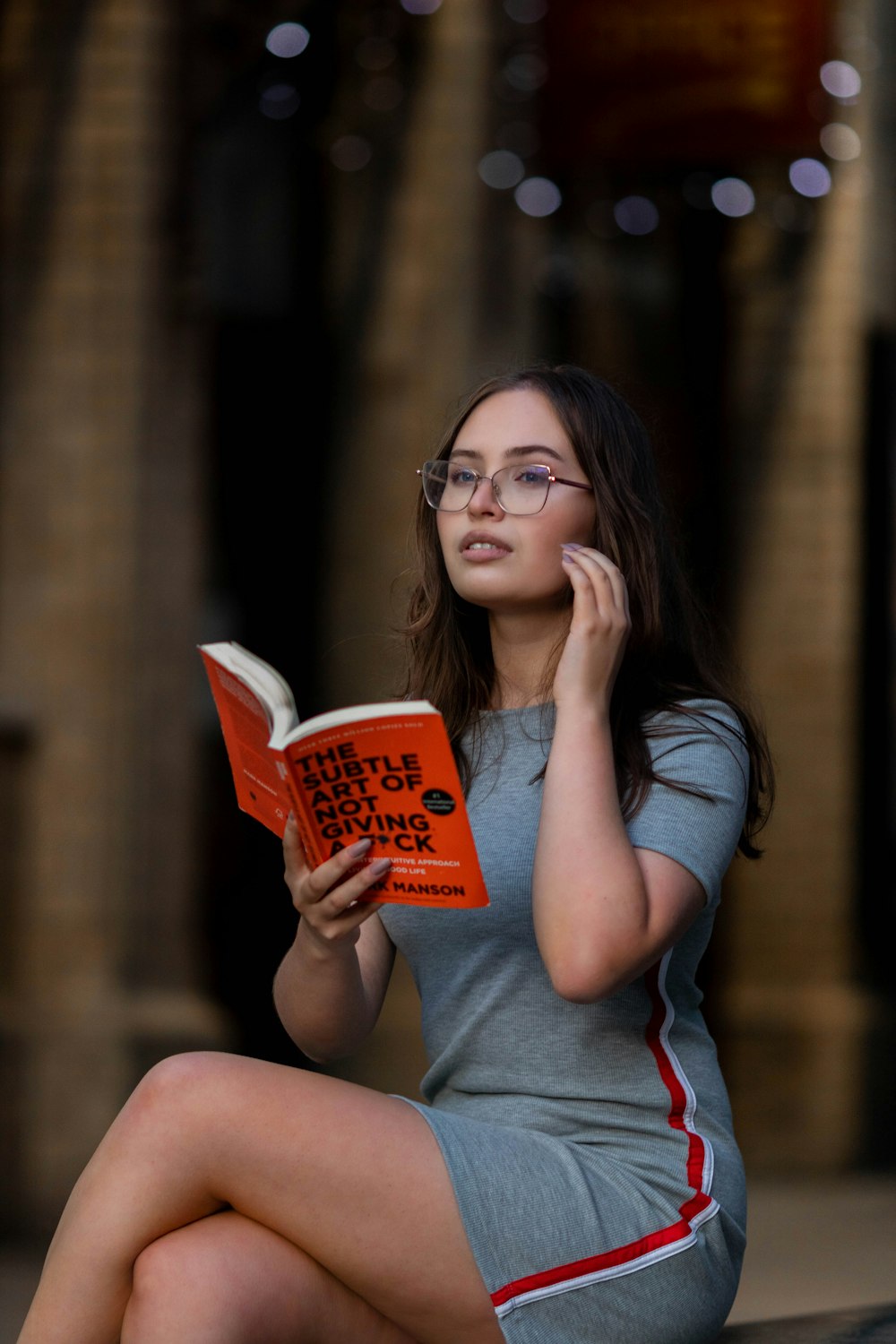 a woman sitting on the ground reading a book