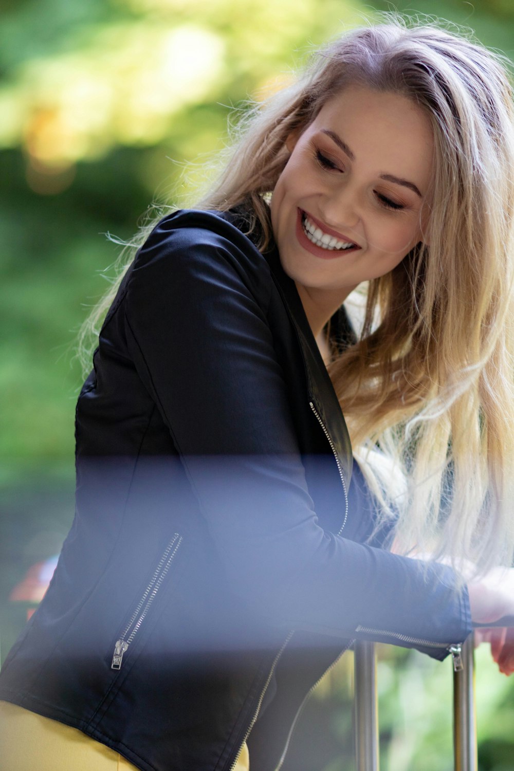 a woman leaning on a rail smiling at the camera