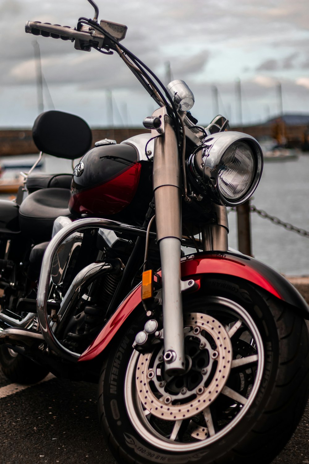a red and black motorcycle parked next to a body of water