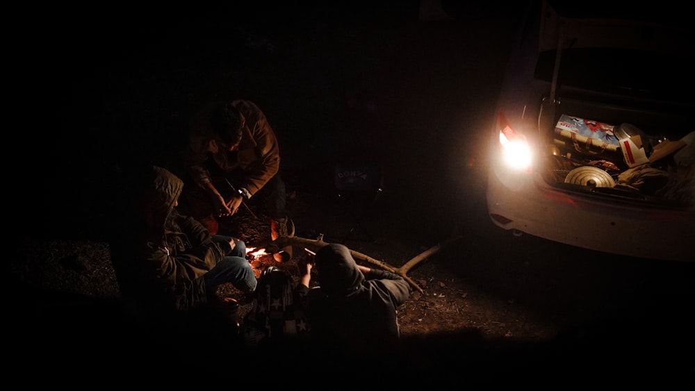 a group of people sitting around a campfire in the dark