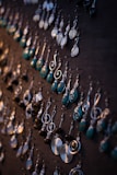 A selection of colorful gemstone earrings displayed on a rustic wooden board
