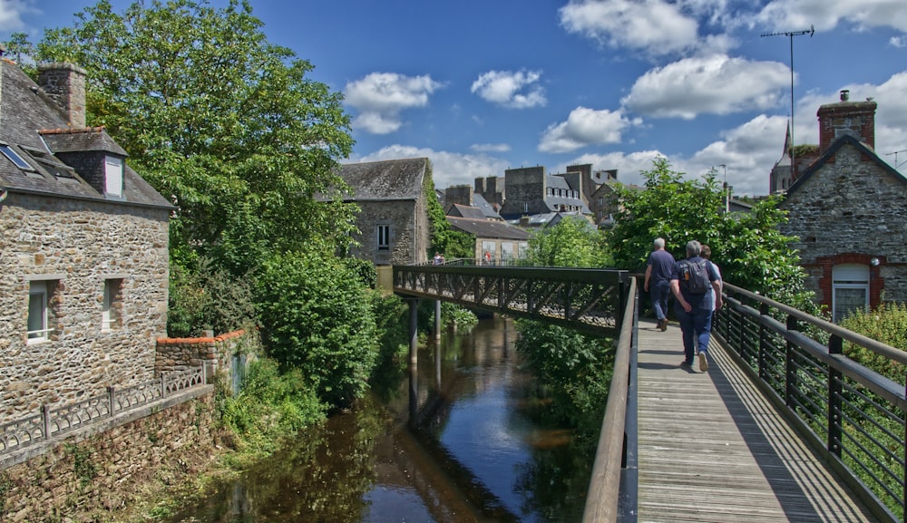 two people walking across a bridge over a river