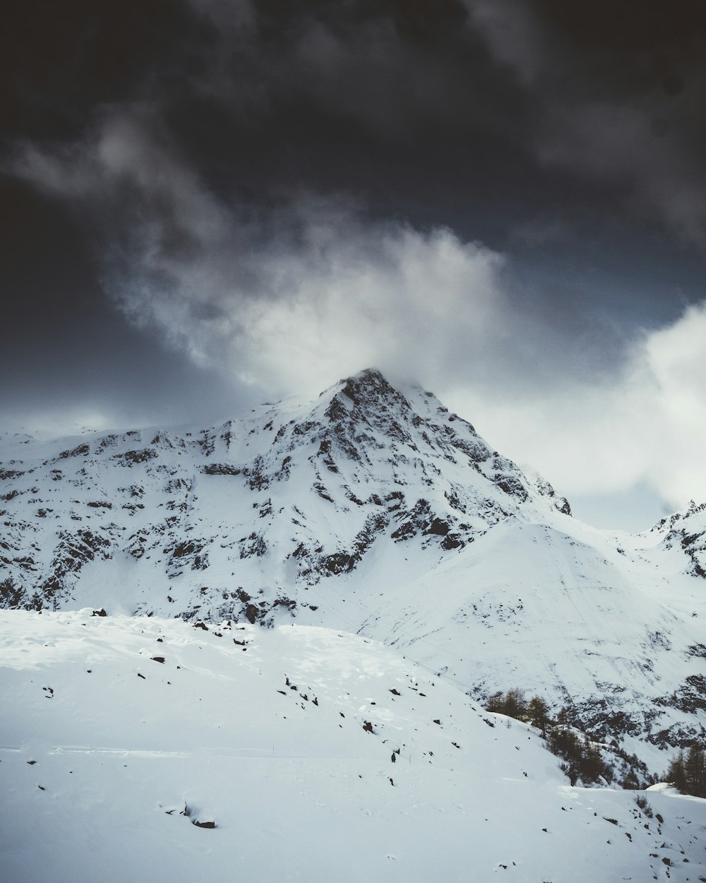 a mountain covered in snow under a cloudy sky