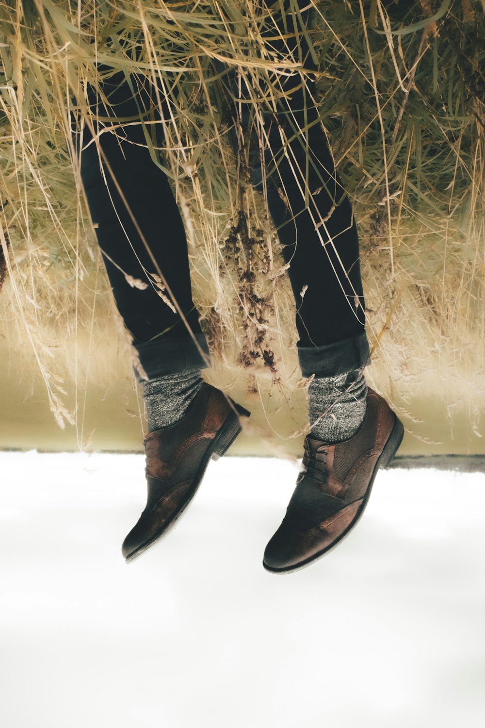 a person standing in front of a bunch of dry grass