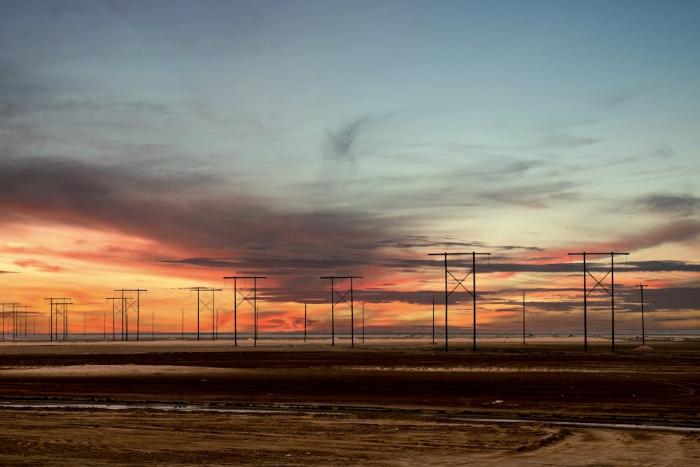 a line of power poles in the distance with a sunset in the background