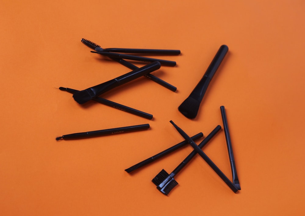 Eine Gruppe schwarzer Stifte, die auf einer orangefarbenen Oberfläche sitzen