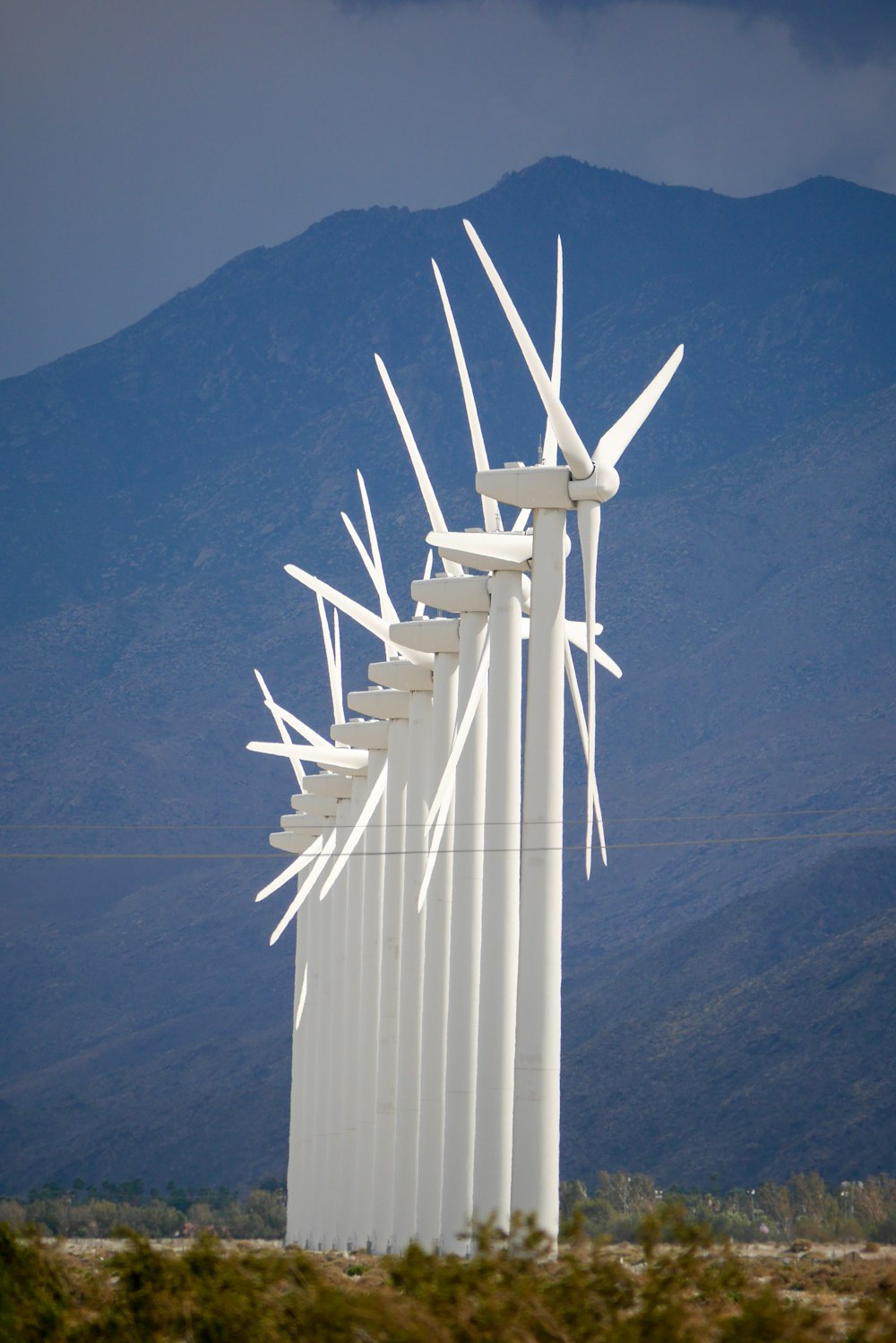 a row of wind turbines in front of a mountain