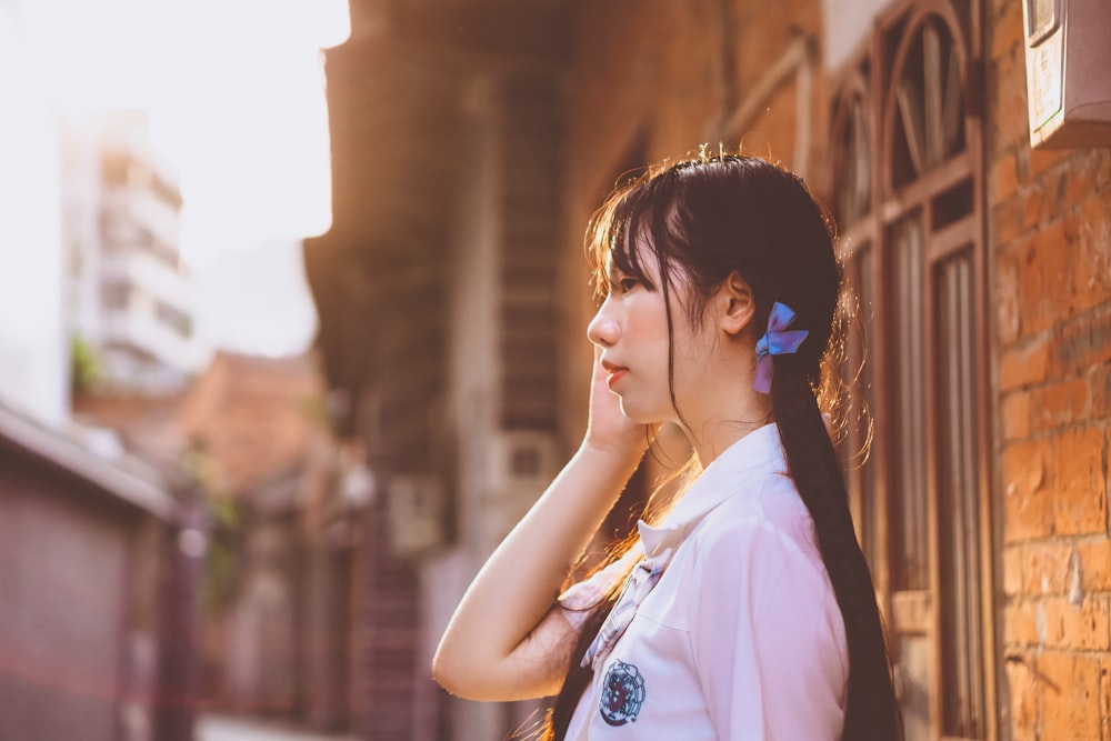 a woman with a ponytail standing next to a brick building