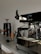 A sleek coffee machine with a steaming cup of coffee and coffee beans around it.