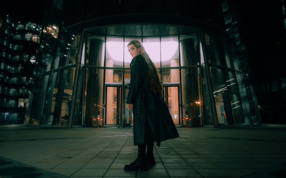 a woman standing in front of a building at night