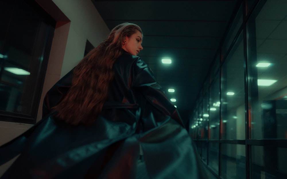 a woman with long hair is walking down a hallway
