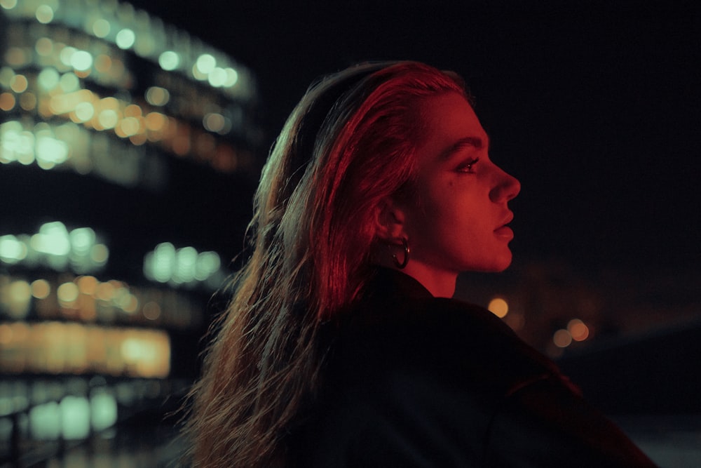 a woman standing in front of a city at night