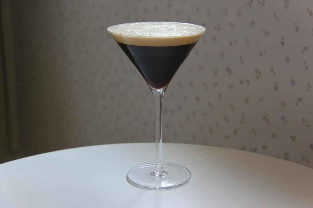 Un bicchiere da martini pieno di liquido sopra un tavolo bianco