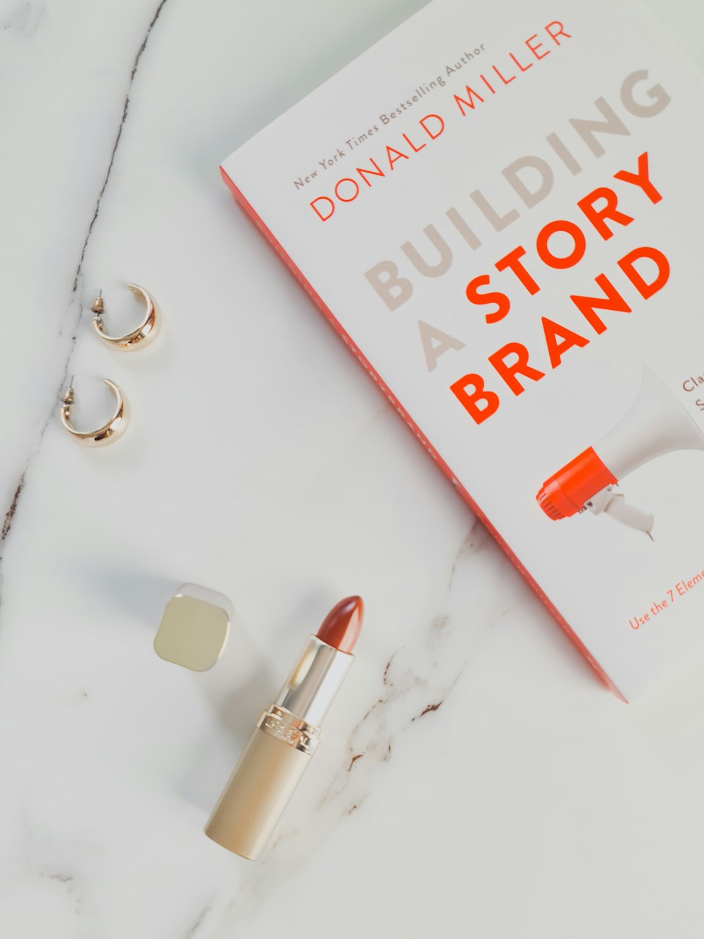 a book and lipstick on a marble table