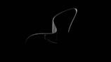 A sleek and minimalistic object with smooth curves is highlighted against a dark background. The object appears glossy and has a flowing, abstract form.