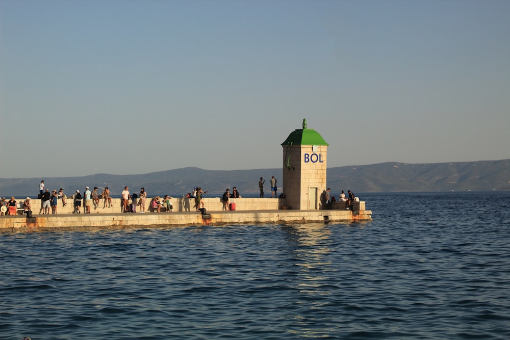 a group of people standing on a pier next to a body of water