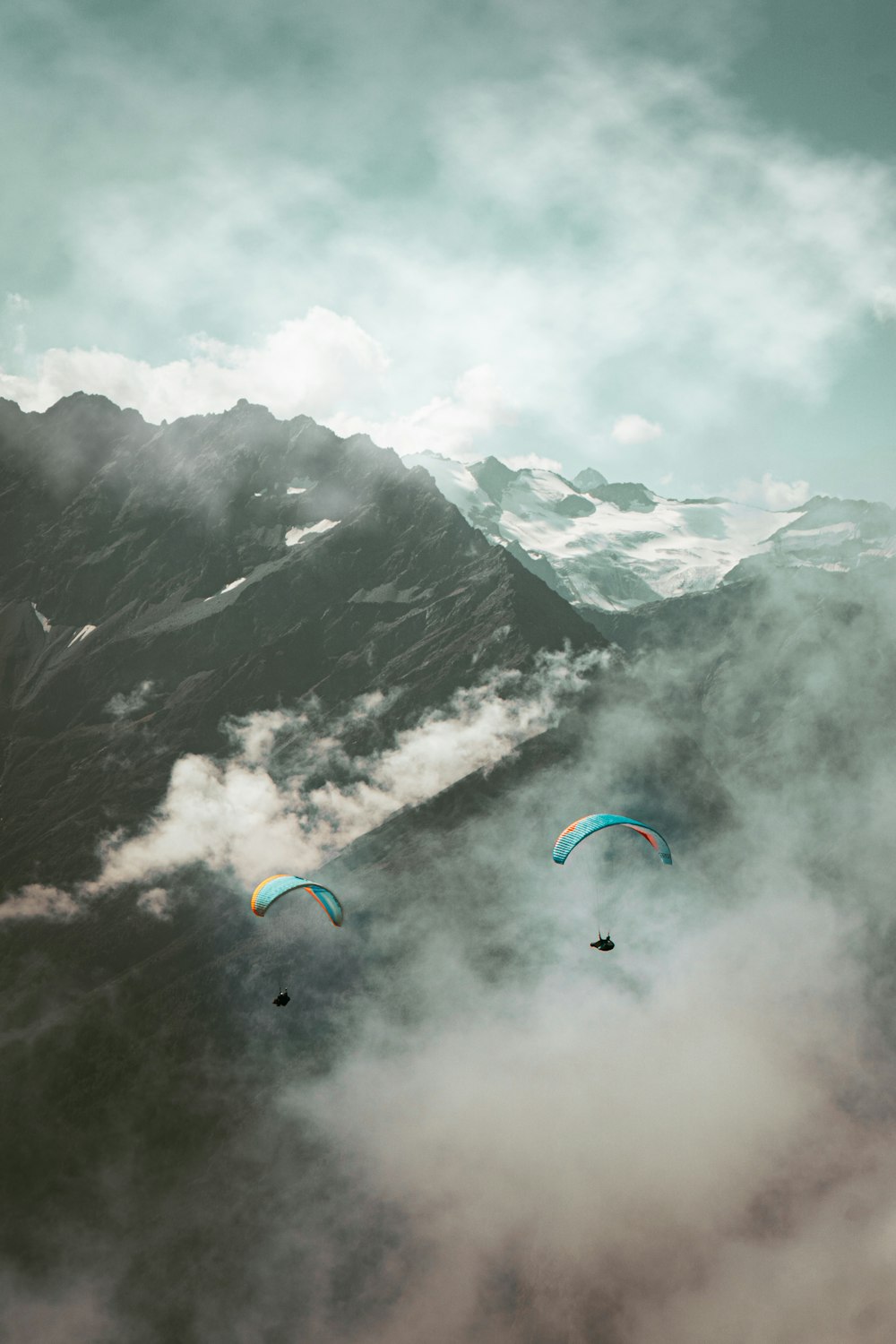 Dos parapentes vuelan sobre una cadena montañosa