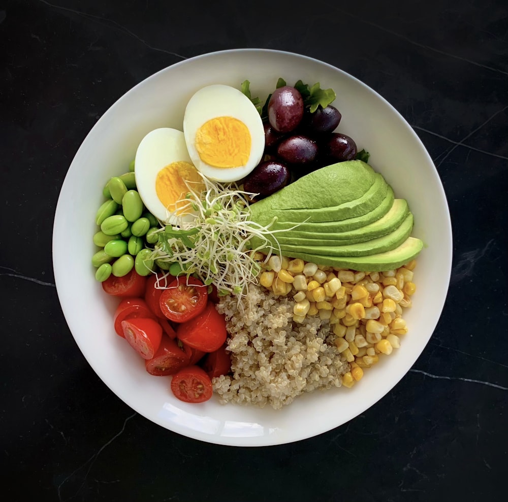 un tazón blanco lleno de verduras y huevos