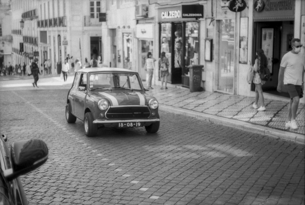 a small car driving down a street next to tall buildings