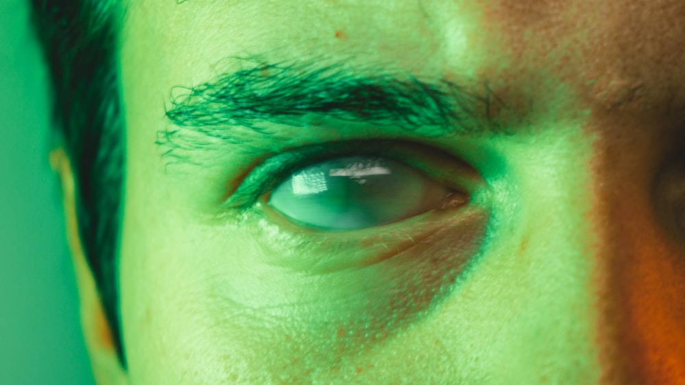 um close up do olho de um homem com um fundo verde