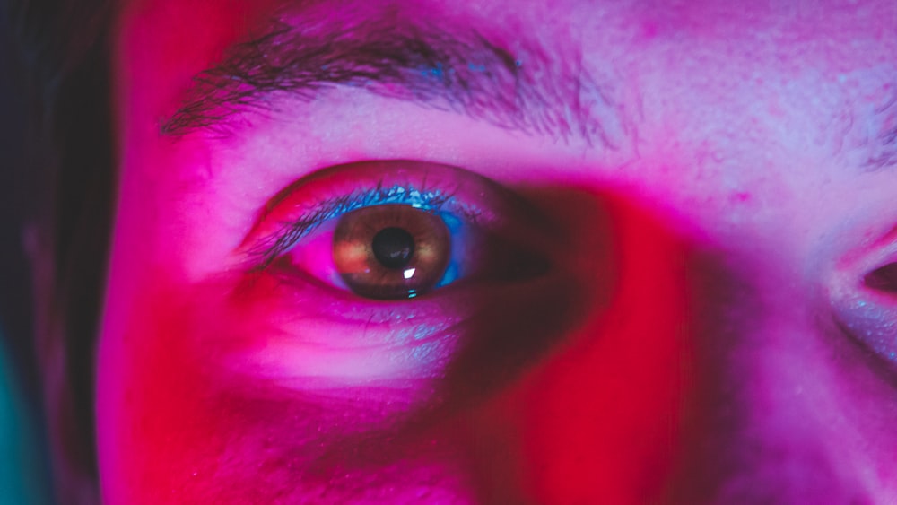 a close up of a person's eye with a red and blue background