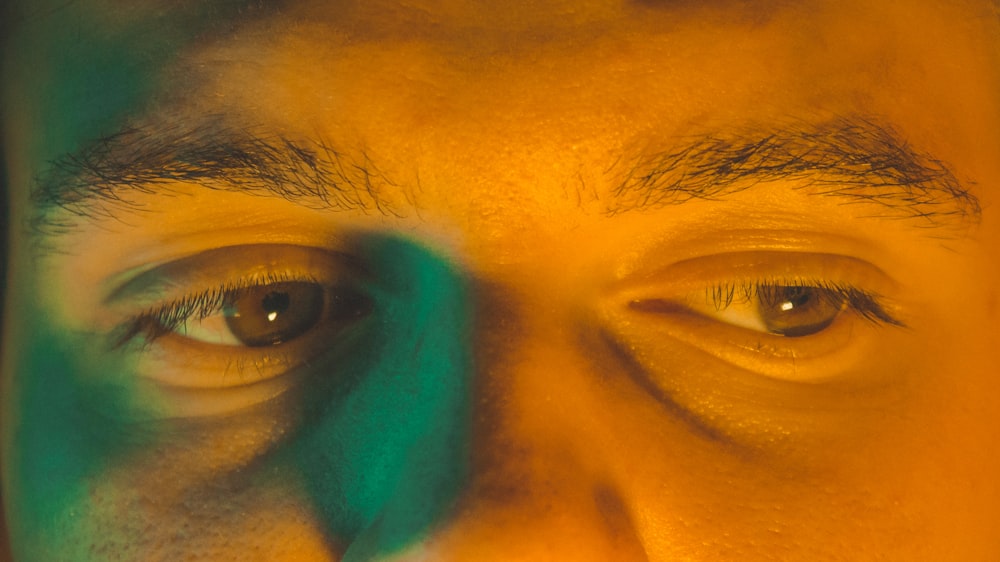 a close up of a man's face with green and yellow shadows