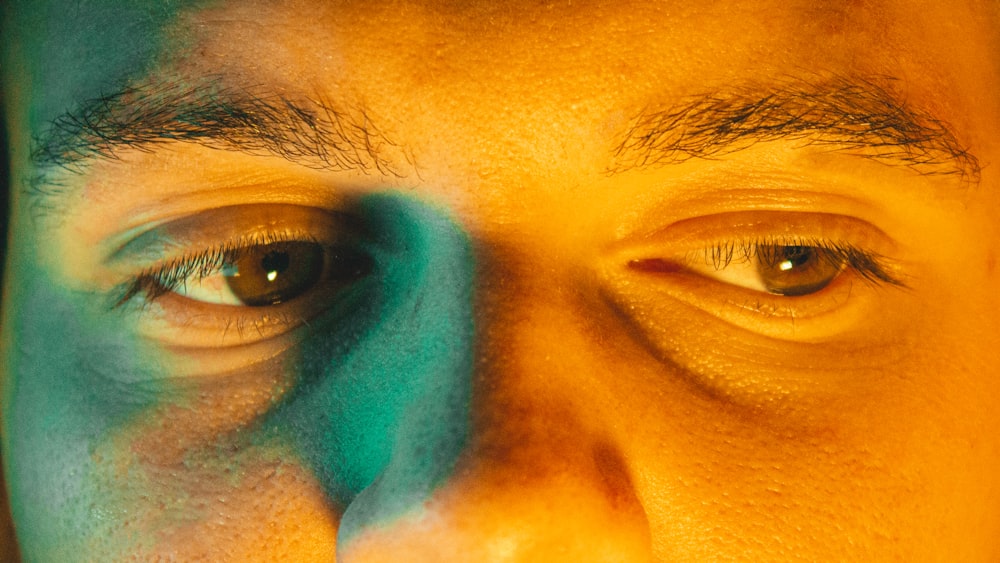 a close up of a man's face with a green and blue shadow on