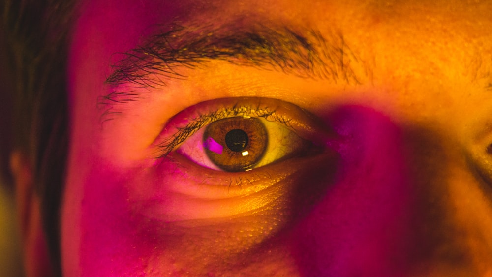 a close up of a man's eye with pink light