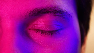 a close up of a person's eye with a purple light