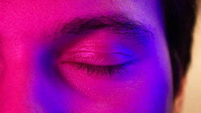 a close up of a person's eye with a purple light