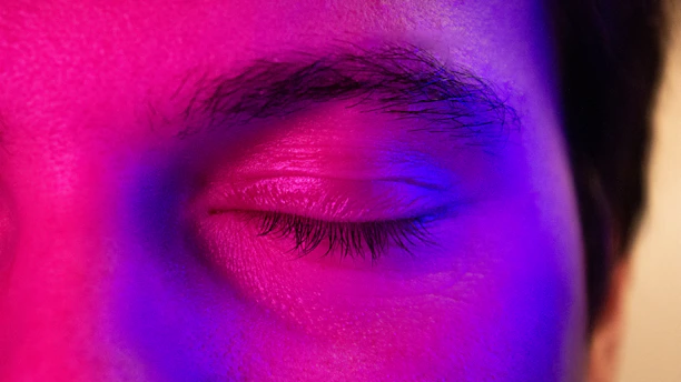 a close up of a person's eye with a purple light