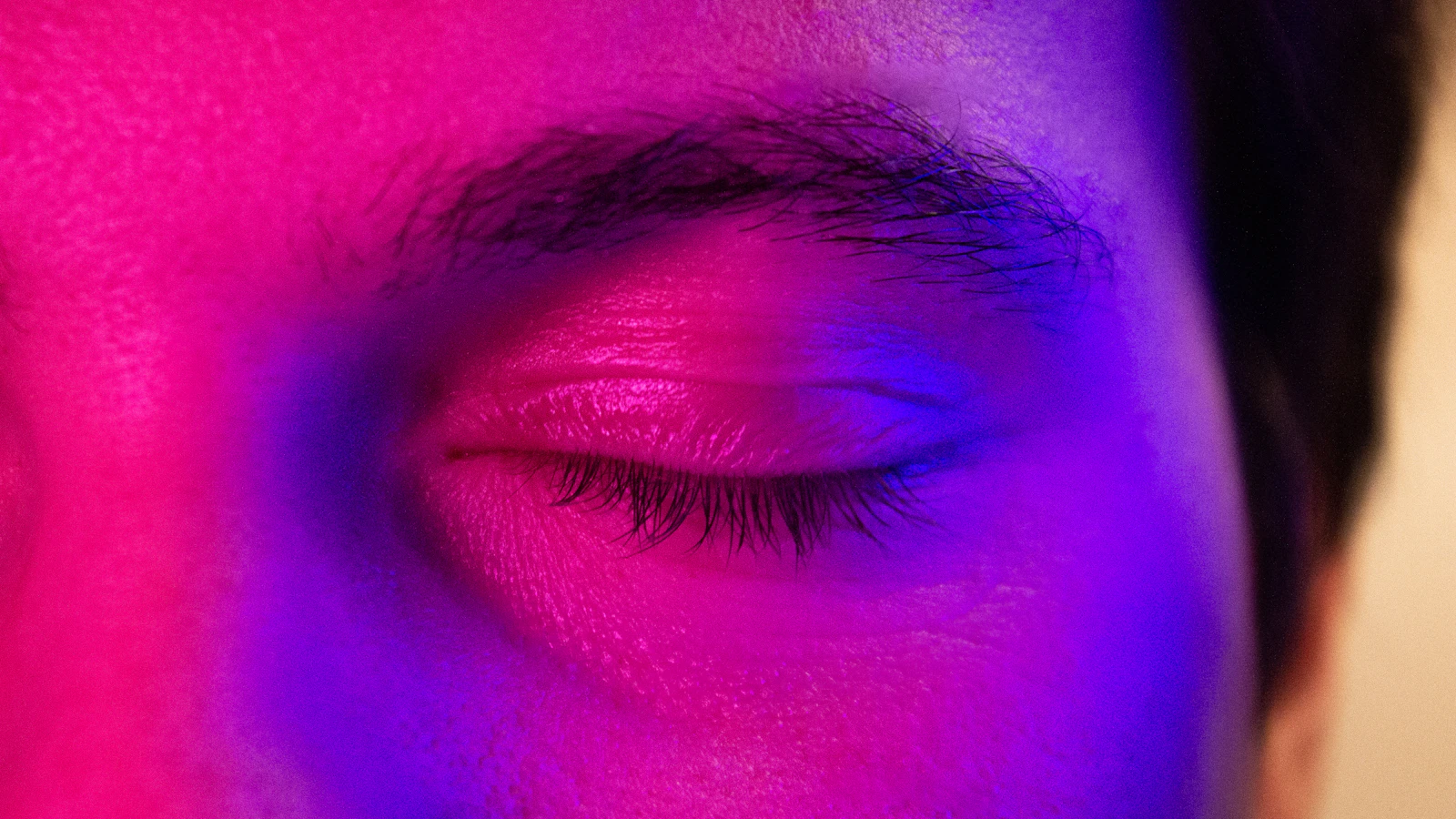 Extreme close-up of a human eye lit with purple light, illustrating lucid dreaming awareness