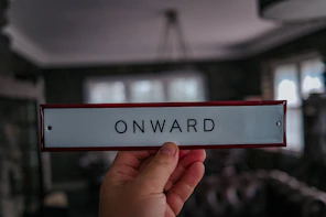 a hand holding a sign that says onward