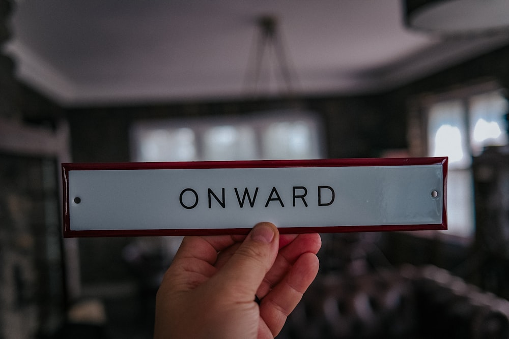a hand holding a sign that says onward