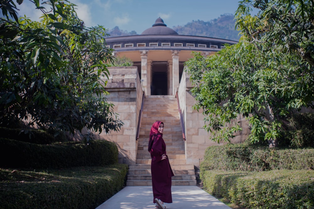 a woman in a red dress standing in front of a building