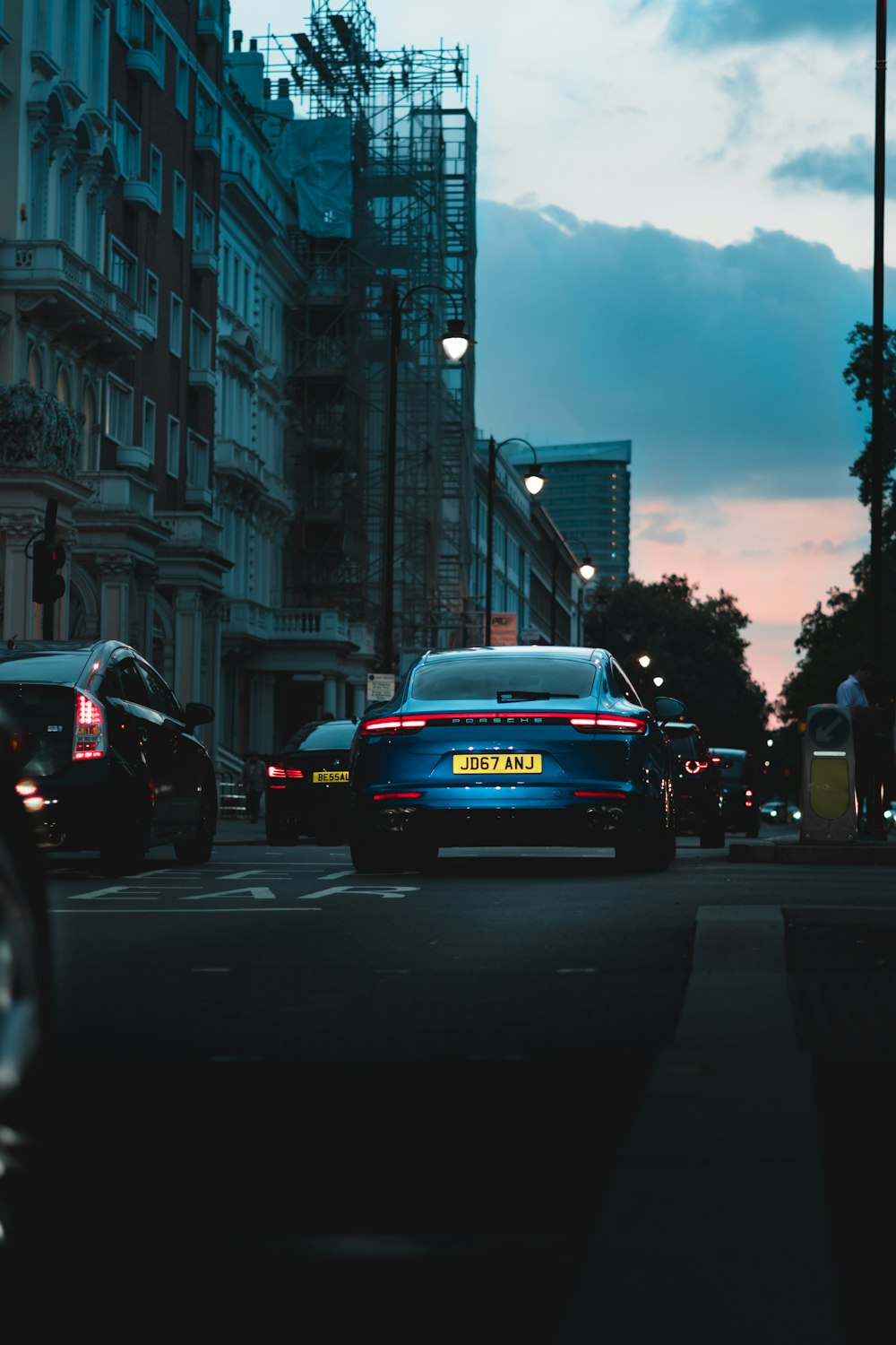 a blue car driving down a street next to tall buildings