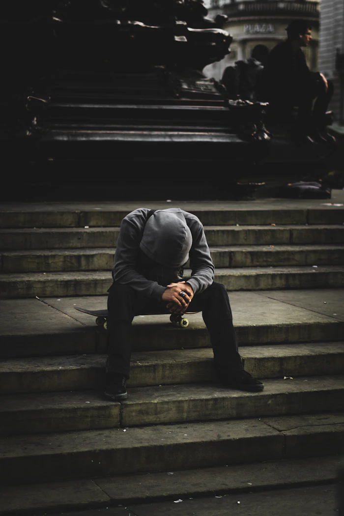 A person sitting on steps with their head in their hands, on grief during career change