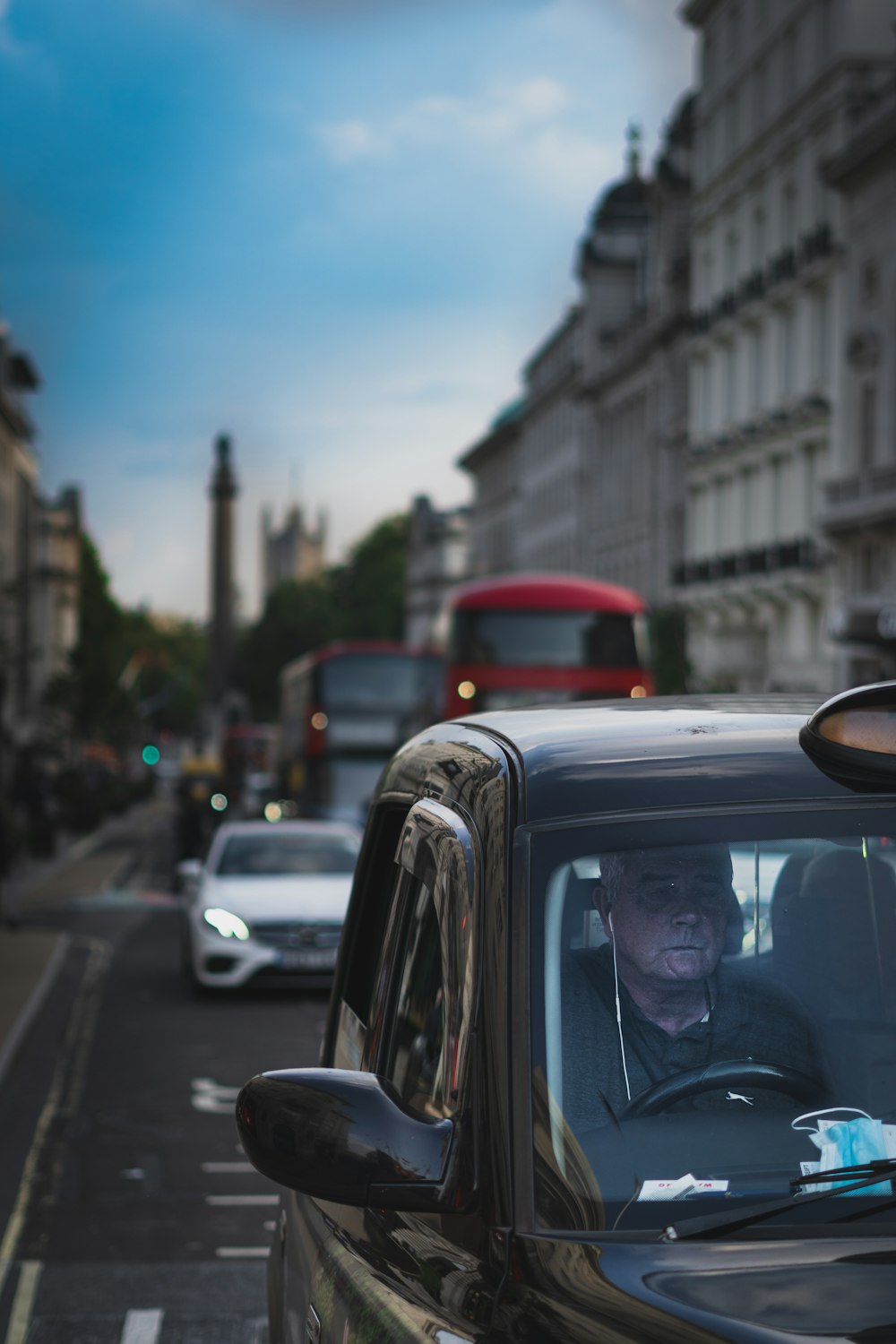 a man driving a car down a street next to tall buildings