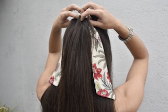 a woman with long hair is putting on a bandana